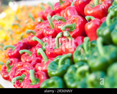 Gelbe, orangefarbene, rote und grüne Paprika auf Holztabletts Stockfoto