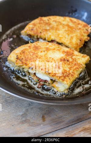 Mozzarella in Carrozza (ein italienisches gebratenes Mozzarella-Sandwich), das in einer Pfanne gebraten wird Stockfoto