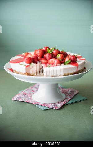 Strawberry Cheesecake mit Erdbeersauce auf einem Kuchen stand Stockfoto