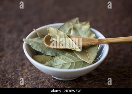 Getrocknete Lorbeerblätter mit einem Holzlöffel in einer Schüssel Stockfoto