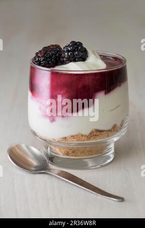 Blackberry cheesecake gemacht withcream Käse, Sahne, black Coulis und zerdrückten Kekse in einem Glas serviert. Stockfoto