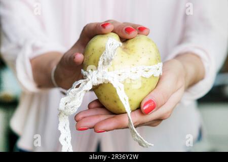 Die Hände einer Frau mit einem Herzförmigen Kartoffel Stockfoto