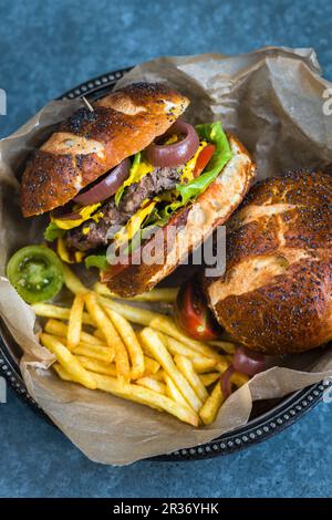 Burger in Brezelbrötchen mit Pommes Stockfoto