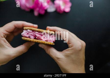 Hände halten Kirscheis-Sandwich mit Waffeln Stockfoto