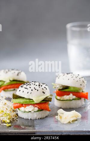 Drei Sushi-Burger mit geräuchertem Lachs, Gurke, frischem Käse, Wasabi, Nori und Avocado Stockfoto