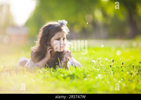 Süßes Mädchen, das Löwenzahn bläst Stockfoto