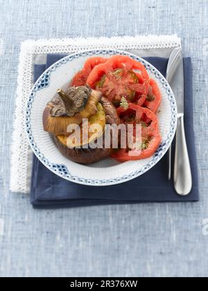 Eine gefüllte Aubergine, serviert mit Tomatensalat Stockfoto