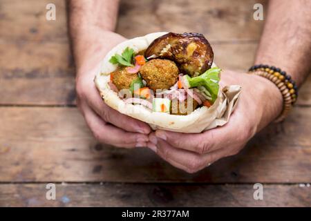 Hände halten ein Pita-Brot mit Falafel Stockfoto