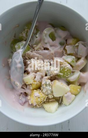 Müsli mit Haferbrei, Trauben, Mango, Äpfel, getrocknete Kokosnuss und Joghurt aus Kokosmilch Stockfoto