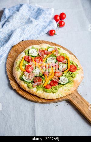 Pizza mit Avocado, Zucchini, Tomaten, Paprika und Schinken Stockfoto