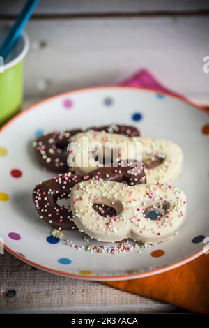 Streuen Sie Kekse (Karnevalsmaske) mit Schokoladenglasuren und bunten Zuckerperlen Stockfoto