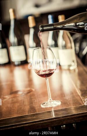 Rotwein wird in ein Glas gegossen Stockfoto