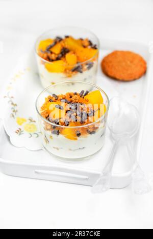 Cremigen Joghurt mit Müsli, Eingemachte Pfirsiche und Schokolade Rollen Stockfoto