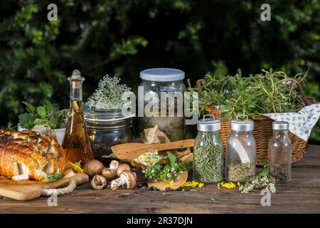 Verschiedene Wildkräuter (frisch, getrocknet und in Gläsern), Pilze, Kräuterbutter und Brot auseinanderziehen Stockfoto