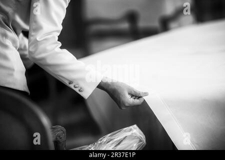 Ein Kellner ziehen eine Tischdecke über einen Tisch im Restaurant Stockfoto