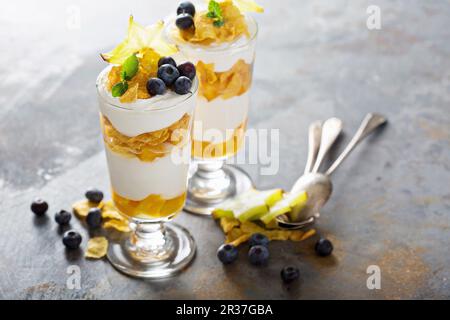 Joghurt-Müsli-Parfait mit Mango und tropischen Früchten, geschichtete Dessert oder Frühstück Stockfoto