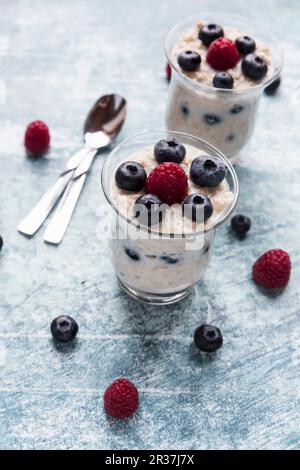 Haferbrei mit Himbeeren und Blaubeeren in zwei Gläsern Stockfoto