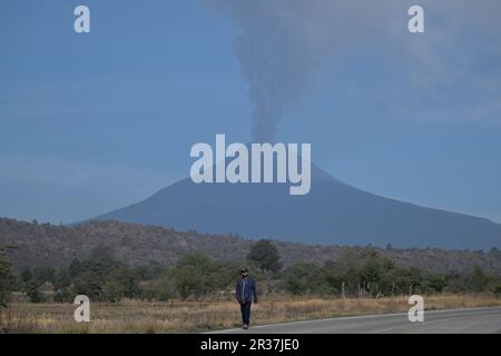 Puebla, Mexiko. 22. Mai 2023. Im Bundesstaat Puebla, Mexiko, am 22. Mai 2023 wandelt ein Mann, während der Vulkan Popocatepetl eine Aschewolke emittiert. Am Sonntag erhöhten die mexikanischen Behörden die Alarmstufe aufgrund der jüngsten erhöhten Aktivität des Vulkans Popocatepetl. Die Alarmstufe wurde von der gelben Phase zwei auf die gelbe Phase drei erhöht, einen Schritt unter der roten Alarmstufe, sagte Laura Velazquez, Leiterin der mexikanischen Nationalen Katastrophenschutzbehörde, bei einer Pressekonferenz. Kredit: Xin Yuewei/Xinhua/Alamy Live News Stockfoto