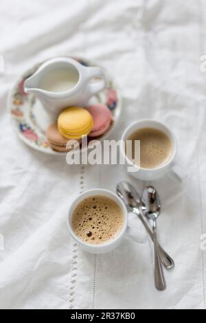 Zwei Tassen Kaffee mit einem Milchkännchen und Makronen Stockfoto