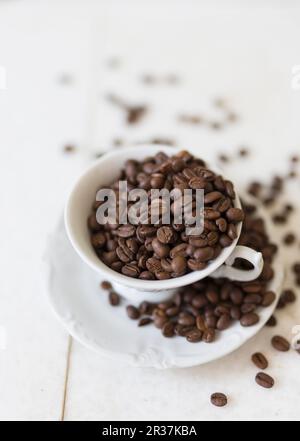 Kaffeebohnen in einer Kaffeetasse und auf einer Untertasse Stockfoto