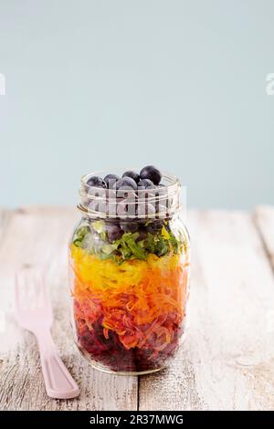 Rainbow Salat in einem Glas mit Rote Bete, Karotten, gelbe Paprika, Salat und Blaubeeren Stockfoto