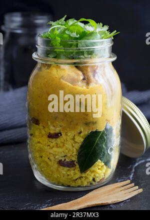 Cremige malaysischen Chicken Curry mit Kurkuma, Kokos, Zimt und Rosinen Reis. Mit einer Handvoll frischer Koriander Blätter gekrönt. Stockfoto