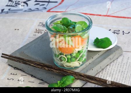 Zutaten für asiatische Nudelsuppe mit Gemüse schichtweise in ein Glas Stockfoto