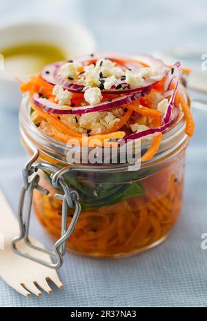 Karottensalat mit Muttern, Feta, Spinat, roten Zwiebeln, Olivenöl und schwarzem Sesam in einem Marmeladenglas Stockfoto