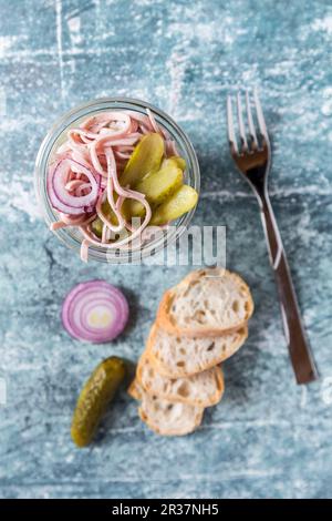 Eine Wurst, rote Zwiebel und Gurke Salat im Glas, mit Baguette Scheiben Stockfoto