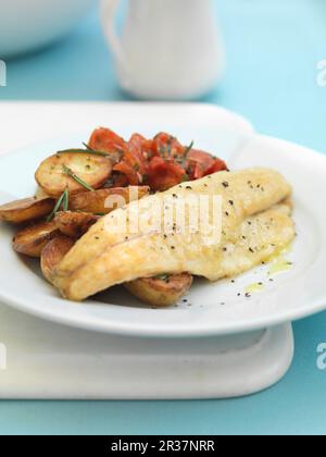 Seebarsch mit gebratenen Kartoffeln und Tomaten Stockfoto