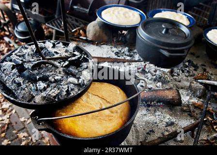 Brot backen in einem holländischen Ofen über einem Kamin (Camping) Stockfoto