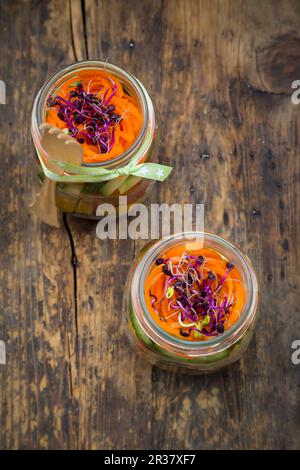 Regenbogensalat in Glasgefäßen mit Rotkohl, gelbem Pfeffer, Tomaten, Gurken, Karotten und Rote-Beete-Sprossen Stockfoto