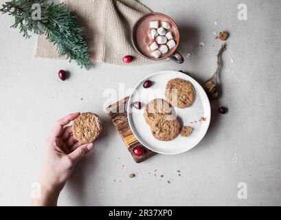 Glutenfreie Kekse auf einem Teller mit einer Tasse heißer Schokolade und Marshmallows dahinter Stockfoto