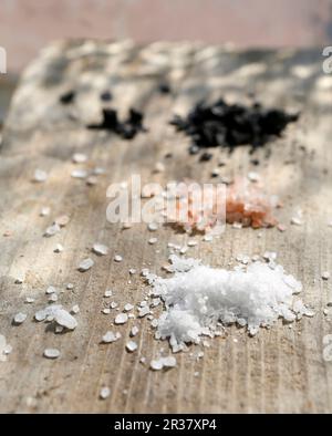 Weißes, rosafarbenes und schwarzes Salz auf einem hölzernen Hintergrund Stockfoto