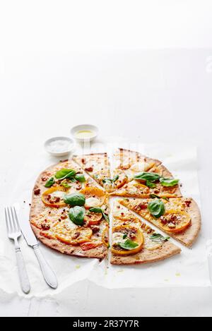 Glutenfreie hausgemachte Pizza mit Persimonen, Ziegenkäse und Basilikum Stockfoto