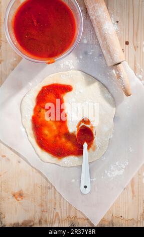 Tomatensauce auf gerolltem Pizzateig Stockfoto