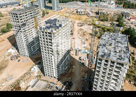 Nahaufnahme aus der Vogelperspektive von im Bau befindlichen Hochhaus-Wohngebäuden und Arbeitskränen. Stockfoto