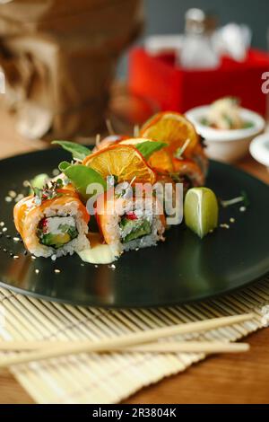 Sushi-Brötchen mit Lachs, Avocado, frischem Käse und Kräutern Stockfoto