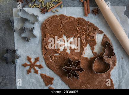 Vegane Lebkuchen, die aus einem ausgerollten Gebäckstück geschnitten werden (von oben gesehen) Stockfoto