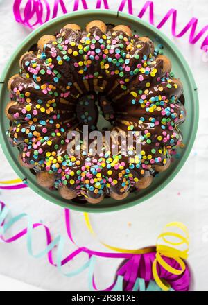 Ein Gugelhupf mit Schokoladenglasur und Zuckerkonfetti für einen Karneval Stockfoto