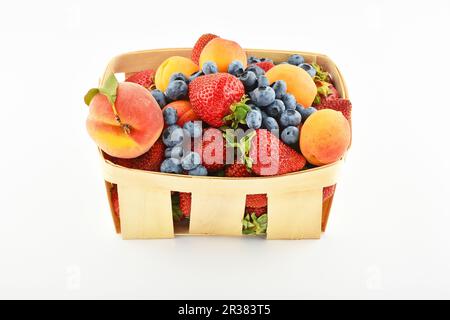 Erdbeeren, Aprikosen, Heidelbeeren, Pfirsiche im Korb, isoliert auf weiß Stockfoto