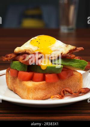 Ein Spiegelei, Avocado und Speck auf Toast zum Brunch Stockfoto