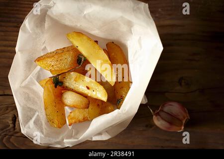 Hausgemachte Kartoffelkeile in Papier mit Knoblauch Stockfoto