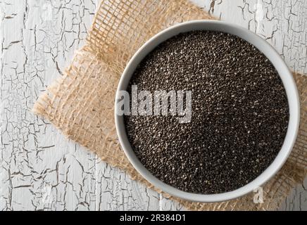 Schwarze Chiasamen in einer Schüssel auf einem rustikalen Holztisch Stockfoto