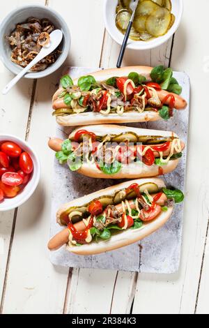 Hot Dogs mit Salat, Tomaten, Gurken, Ketchup, Senf und gerösteten Zwiebeln Stockfoto