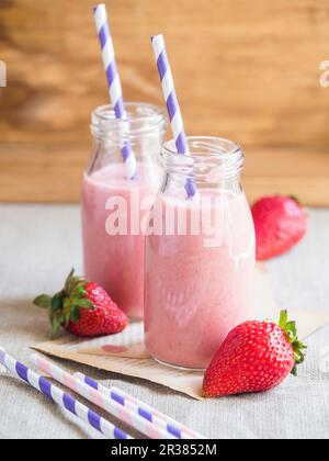 ErdbeerSmoothies in Glasflaschen mit Trinkhalmen Stockfoto