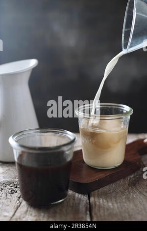 Milch wird in Kaffee gegossen Stockfoto