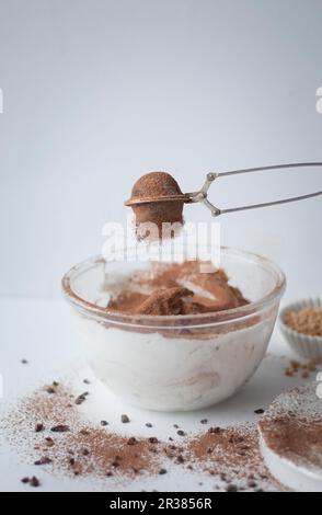 Das Kakaopulver wird in eine Schokoladen-Baiser-Mischung gesiebt Stockfoto