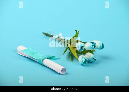 Ein Papier Nachricht und Blüten auf blauem Hintergrund Stockfoto