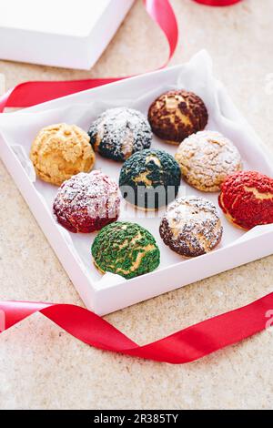 Verschiedenfarbige Choux-Gebäckstücke in einer Geschenkbox Stockfoto